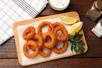 Fried squid rings served on wooden table, flat lay
