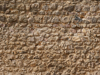 Stone wall made of irregularly shaped stones, part of a building, perfect as a background picture