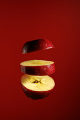 Vibrant red apple halves levitate on red background, symbolizing organic farming, nutritious food,...