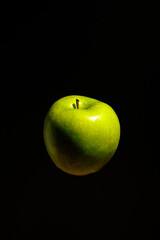 Organic green apple hovering on black background, illustrating healthy living, sports energy, farm produce, vitamins, and balanced nutrition