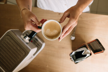 Coffee preparation with barista hands holding a cup in a cozy kitchen setting during midday