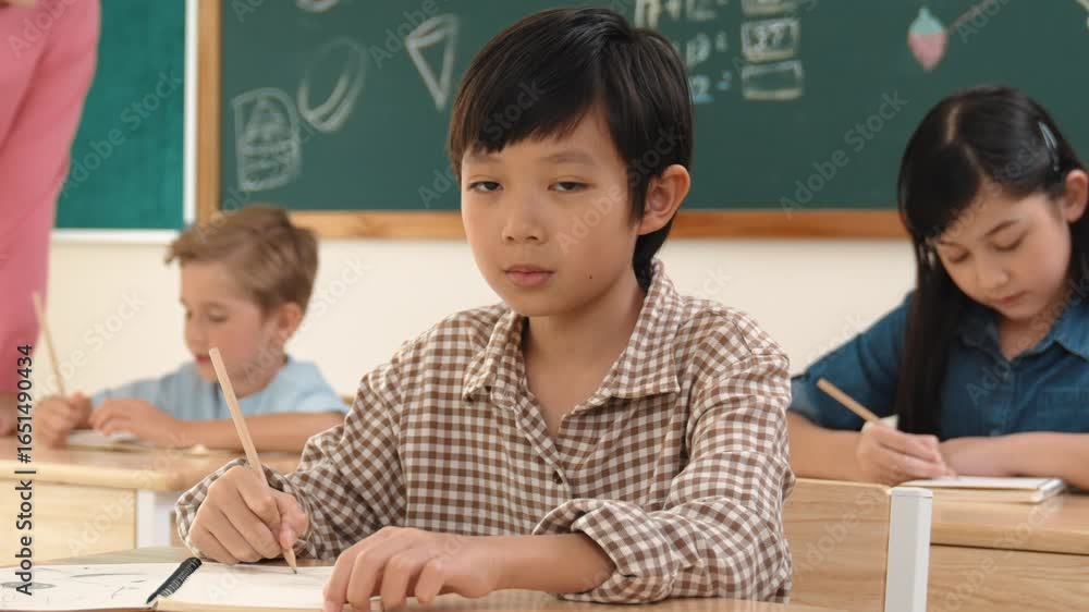 Aufkleber asian smart boy smiling to camera while student writing answer in answer sheet. multicultural studen