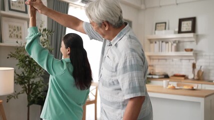 Happy grandfather and grandmother with casual cloth holding hand and dancing together at home. Lovely senior couple moving to music and spending time together while supporting at kitchen. Myrmidon. - Powered by Adobe
