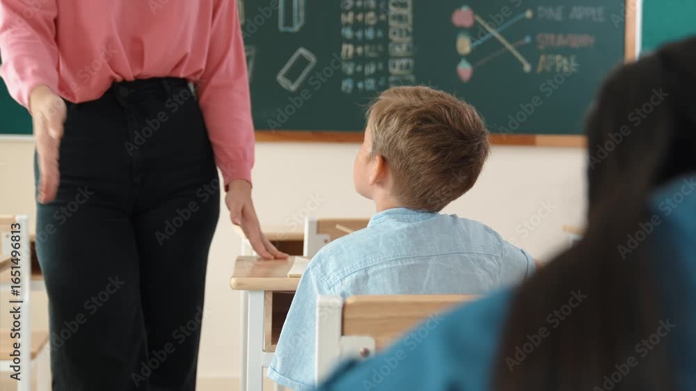 Poster energetic smart teacher explain classwork to caucasian boy at classroom while multicultural student 