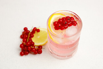 Refreshing drink with red currants and lemon served on a white surface