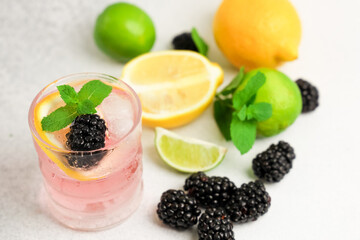 Refreshing blackberry citrus drink with mint and fresh fruits on a marble surface