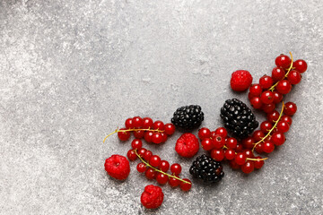 Fresh assortment of red and black berries arranged on a textured gray surface