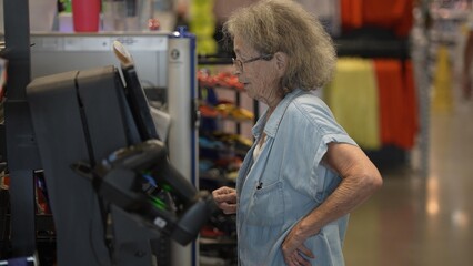 Senior woman with a walker navigates the self checkout at a hardware store, focused on purchasing supplies for her home remodeling project.