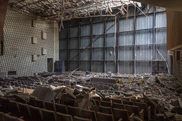 Interior of a destroyed concert hall with collapsed roof and seating after shelling