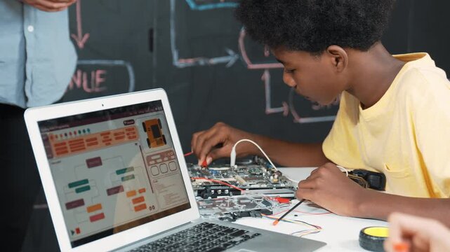 Cute african boy learning to use electronic tool while laptop display code while teacher talking about writing engineering prompt. Diverse children coding program to fixing car model. Edification