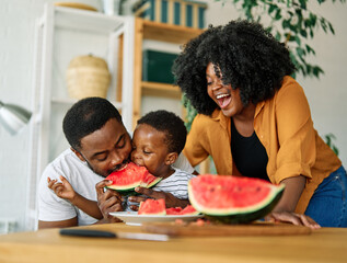 Portrait of family of three, father, mother and son cutting a watermelon fruit and having fun in...