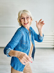 Obraz premium Happy active senior woman, portrait of an elderly woman dancing at home