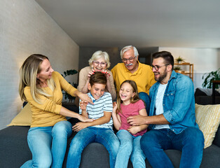 Portrait of a three generation famili, grandparents, parents and children sitting on sofa and...