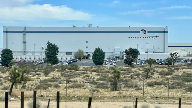 PALMDALE, CA, APR 10, 2025: Large Lockheed Martin industrial facility and aircraft hangar, known as the Skunk Works. Gray exterior, corporate logo, desert landscape with Joshua trees in foreground