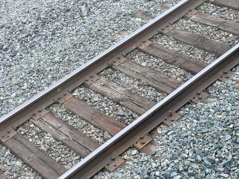 Railway tracks with weathered wooden ties, steel rails, and gravel ballast. Shows the intersection of two rail lines with rustic, industrial infrastructure