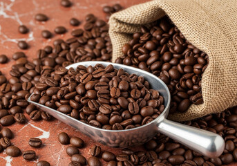 Roasted coffee beans spread across a surface, highlighting rich brown tones, texture, and aroma in a detailed macro shot.
