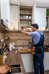 Man organizing shelves in modern kitchen during home renovation project