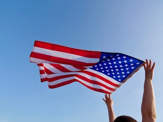 Independence Day American flag against the background of the blue sky blowing in the wind. close up