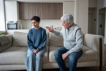 Angry elderly man shouting and blaming wife, senior couple facing domestic issues at home....