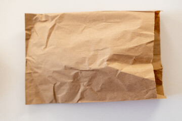 A crumpled brown paper bag lying on a clean surface, showcasing a rustic and natural aesthetic.