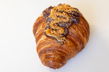 A delicious chocolate caramel croissant, featuring a golden flaky exterior and drizzled toppings, ideal for dessert lovers.