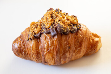 A delicious croissant topped with rich chocolate and crunchy nuts, perfect for a sweet indulgence.