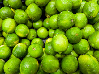 A bunch of green limes are piled on top of each other. The limes are all the same size and shape