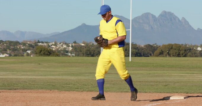 Runner sprinting, male first baseman catching baseball on field with Diverse male teammates hugging