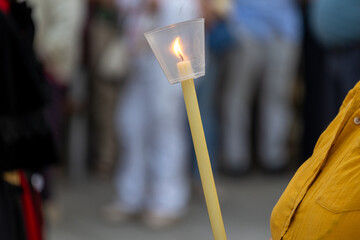 Person holding a lit candle during a public gathering or procession