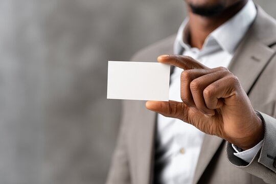Person in suit holding blank card for text or graphic placement.