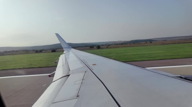 View of the airplane wing from window seat moving through the Chisinau International Airport