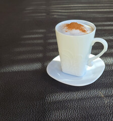Simple white coffee cup on a saucer with steam rising