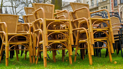 Stacked wicker chairs on a lawn – outdoor seating stored on the grass in a natural setting.