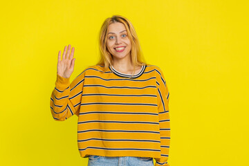 Young Caucasian woman smiling friendly at camera, waving hands gesturing hello hi greeting or...