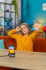 Caucasian teenager boy filming recording trendy selfie video on smartphone at home. Demonstrating...