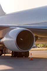 Jet engine close-up with servicing equipment on the airport runway at sunset