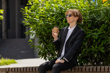 Happy Caucasian businessman enjoying morning coffee hot drink and smiling outdoors. Relaxing,...