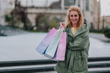 Smiling woman holding shopping bags in urban setting
