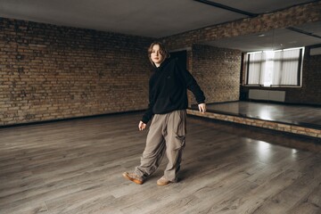 Young dancer practicing movement in an empty studio with wooden floors