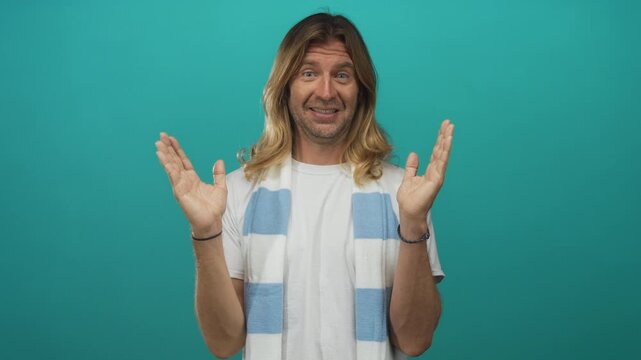 Blond man wearing striped soccer scarf raises hands in cheering gesture in studio; team support enthusiasm.
