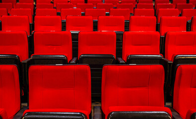 Fototapeta premium Rows of red seats in an auditorium or cinema hall. Evokes entertainment, leisure, and culture.