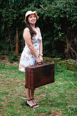 mujer con vestido floral, sombrero y maleta de viaje. estilo vintage, verano.