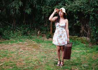 mujer con vestido floral, sombrero y maleta de viaje. estilo vintage, verano.