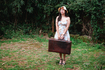 mujer con vestido floral, sombrero y maleta de viaje. estilo vintage, verano.
