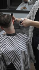 Professional barber grooming client's hair using electric clipper, delivering precise cut with...