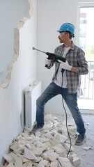 Man construction worker demolishing a wall with a hammer drill in protective gear, creating...
