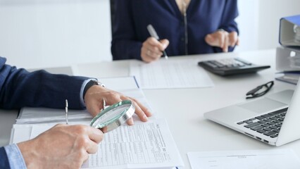 Two professional chartered accountants reviewing financial reports and analyzing data using a...