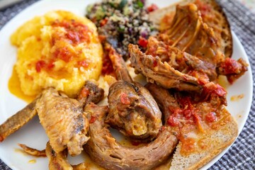 Traditional rustic Brazilian food, guinea fowl, Numida meleagris, with polenta, artisanal bread, and quinoa tabbouleh with vegetables. Real food