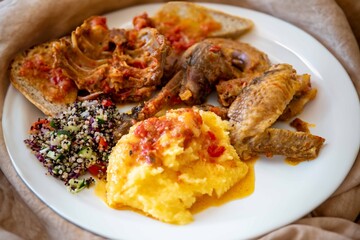Traditional rustic Brazilian food, guinea fowl, Numida meleagris, with polenta, artisanal bread, and quinoa tabbouleh with vegetables. Real food