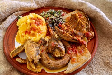 Traditional rustic Brazilian food, guinea fowl, Numida meleagris, with polenta, artisanal bread, and quinoa tabbouleh with vegetables. Real food